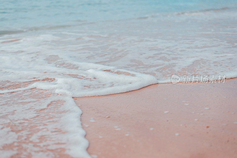 柔软的蓝色海浪和白色的泡沫在沙滩上。