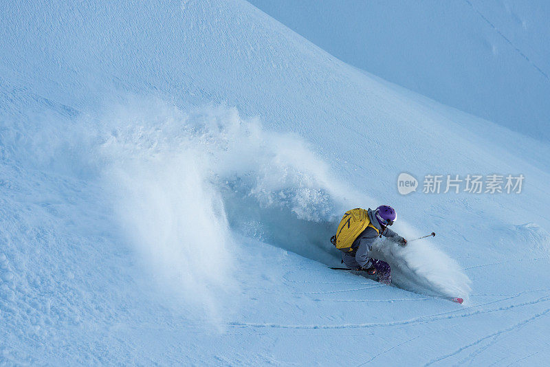 女免费滑雪者在粉雪上转弯