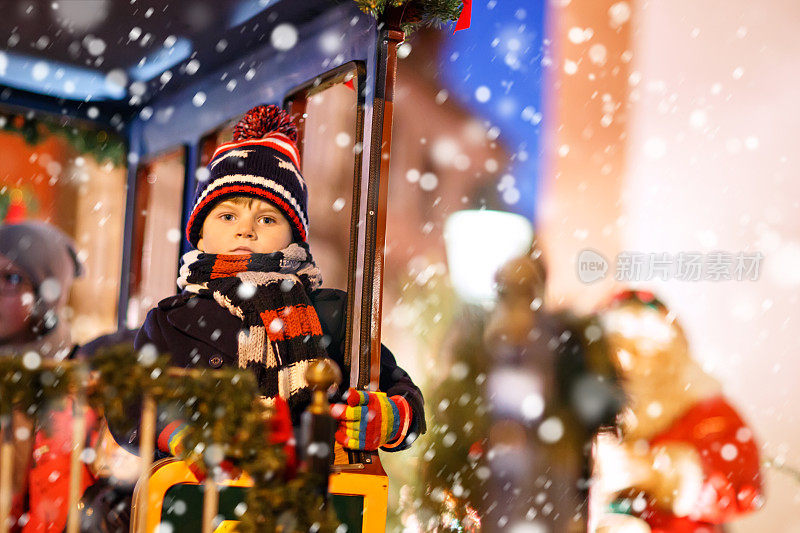 有趣的小男孩在圣诞游乐场或市场的旋转木马上，户外。快乐的孩子玩得开心。传统的圣诞节市场在德国，欧洲。节日、孩子、生活理念…