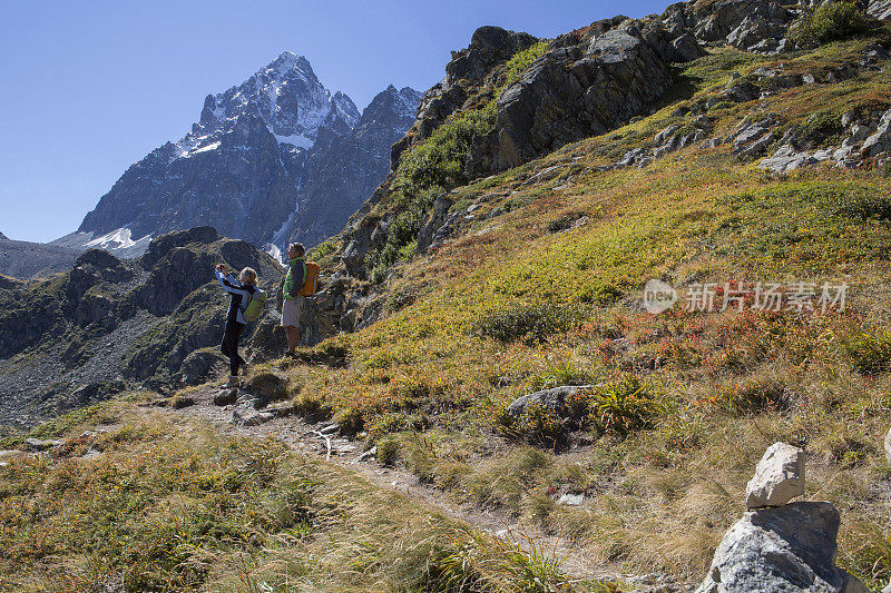 情侣徒步在山上，人行道在前景