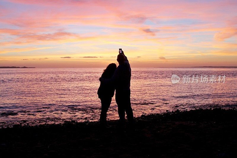 日落时分海滩上一对情侣的剪影