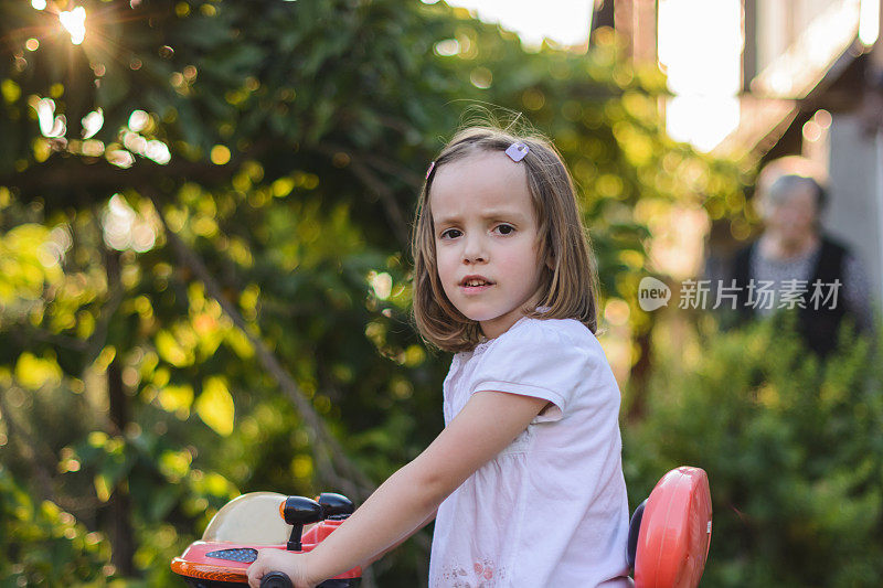 可爱的小女孩骑着三轮车。