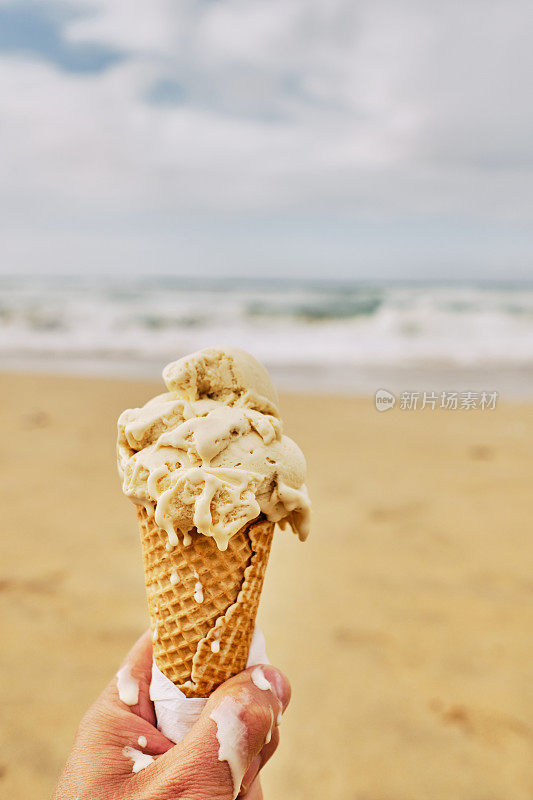 在秋天的一天，在纽基，康沃尔的费斯特拉海滩，POV手拿一个融化的冰淇淋。