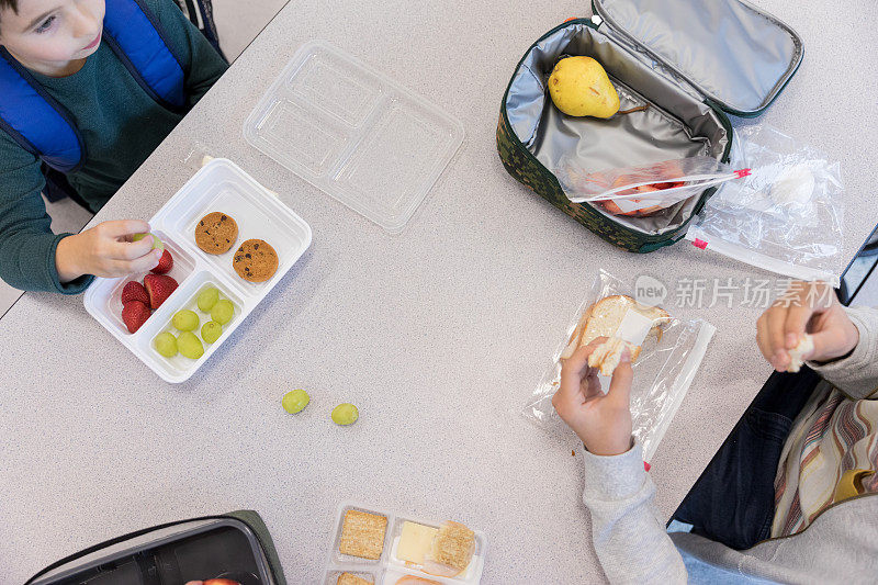 高角度观看男孩在学校食堂吃健康午餐