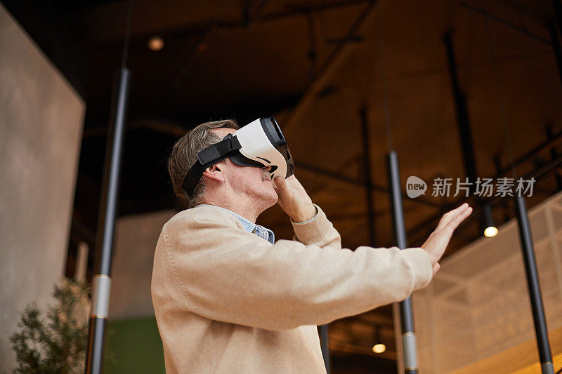 下图是一名戴着虚拟现实眼镜的老年男子在玩视频游戏时打手势