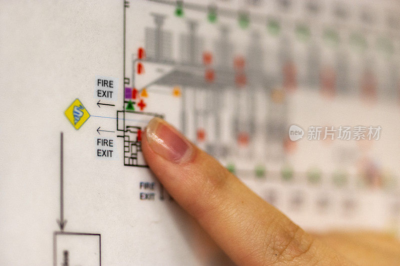 一根手指指着大楼平面图上的紧急出口