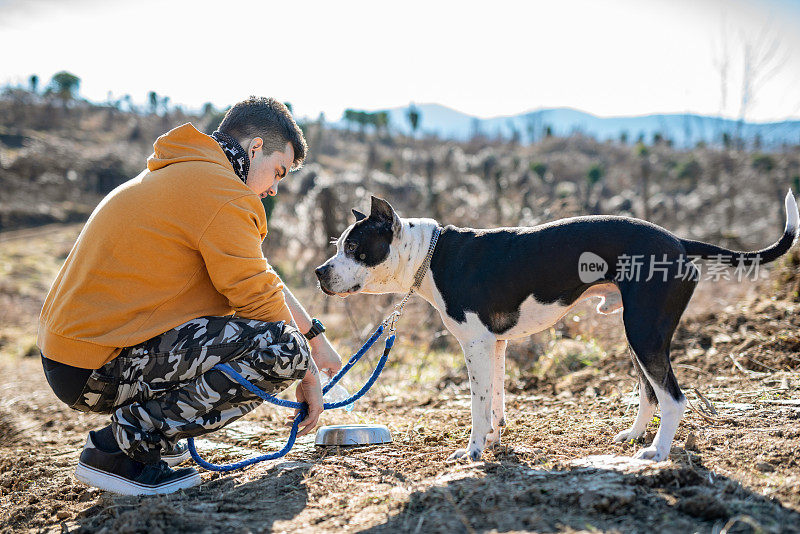 年轻的成年男子在徒步旅行中照顾他的狗