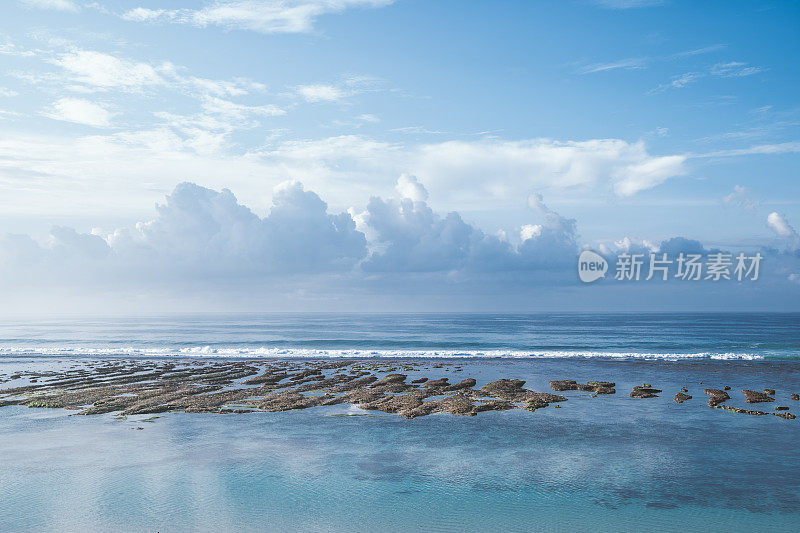 背景是巴厘岛、蓝绿色的印度洋和蓝色多云的天空