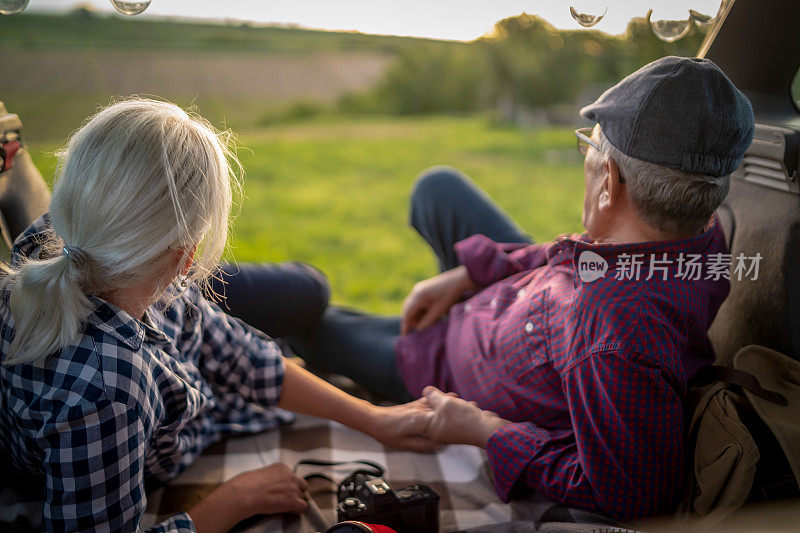 一对快乐的老夫妇坐在他们的汽车后备箱里