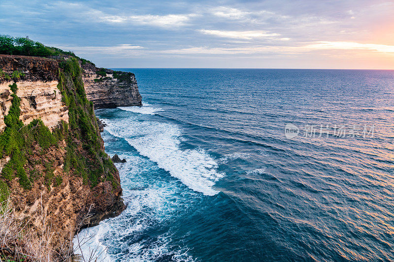 Uluwatu巴厘岛。蓝色的海洋和岩石山，覆盖着热带树木。