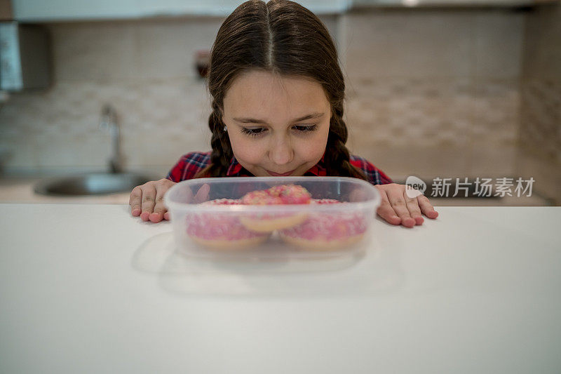 对孩子的饮食。悲伤和不快乐的孩子触及甜甜圈。孩子们的美味食物。孩子在看甜甜圈。垃圾食品上瘾。