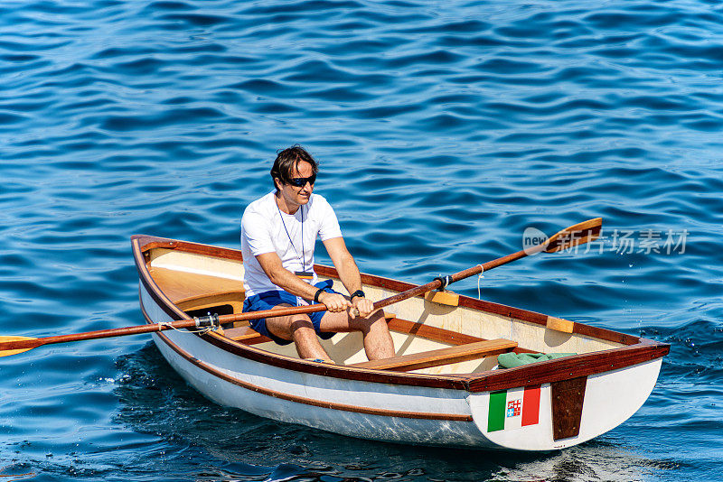 一个男人在一个小木船在蓝色的海洋-意大利利古里亚