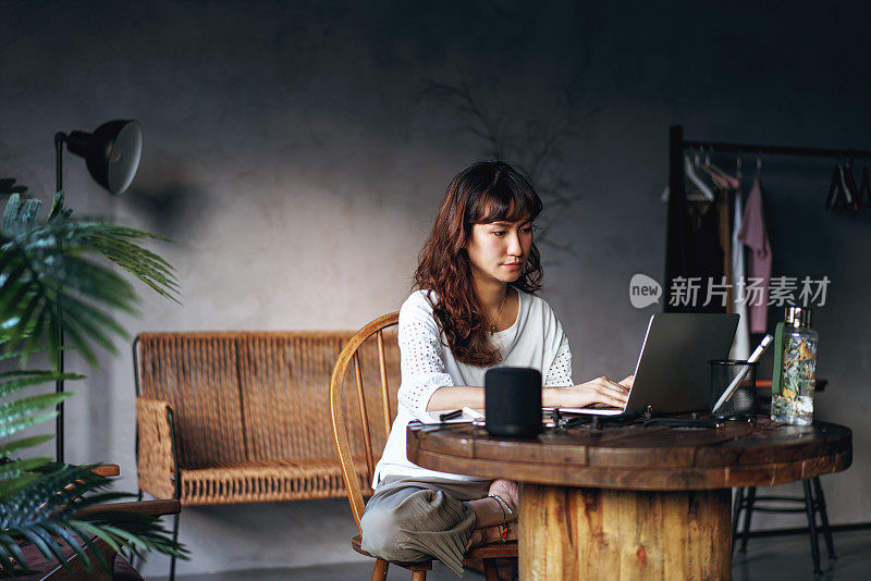 美丽的亚洲女人在家工作与智能扬声器的协助