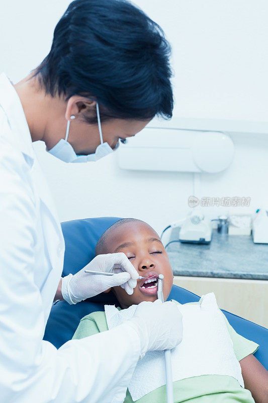女牙医在牙医椅上检查男孩的牙齿