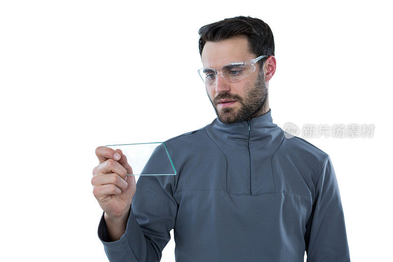 戴着防护眼镜的男子，手上拿着一块玻璃板