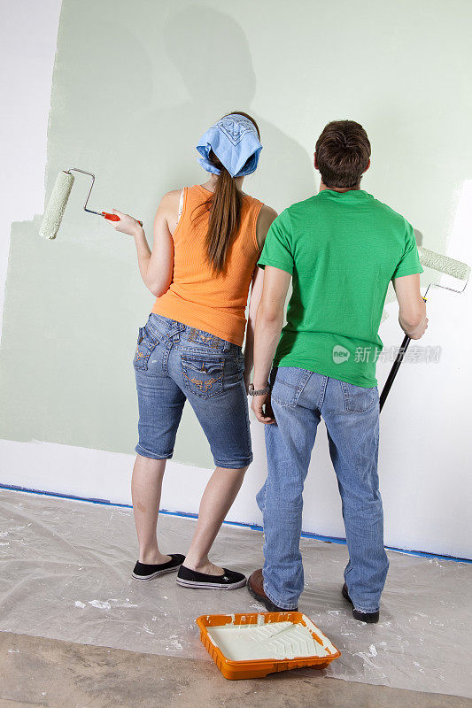 青年夫妇刷墙。首页DIY家居改善项目。