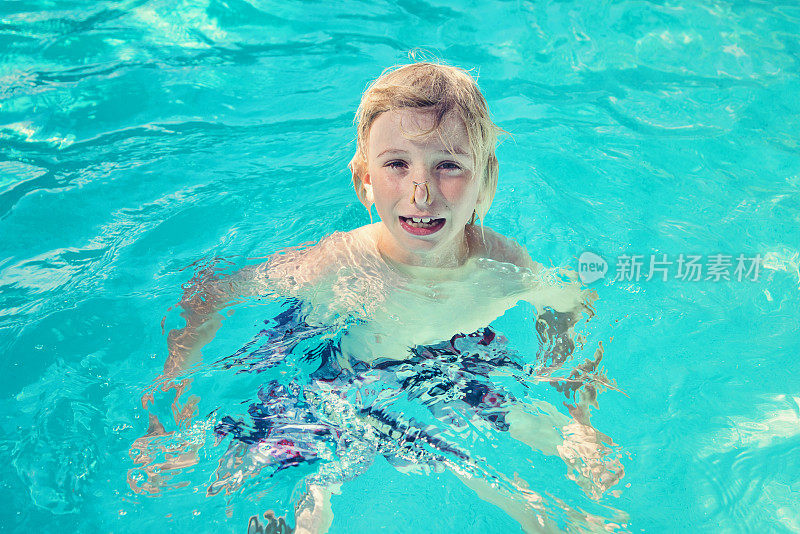 小男孩在泳池里戴着花样游泳用的鼻夹。