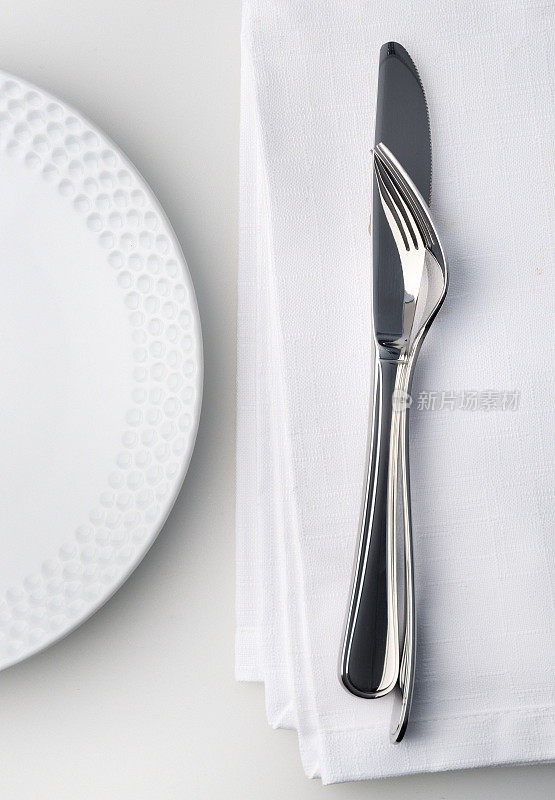 刀叉放在白色亚麻餐巾上。