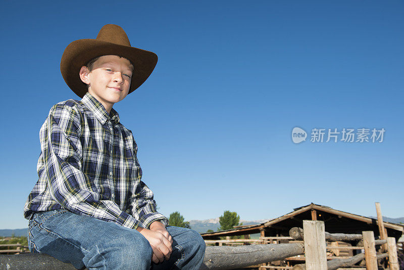 坐在篱笆上的年轻牛仔