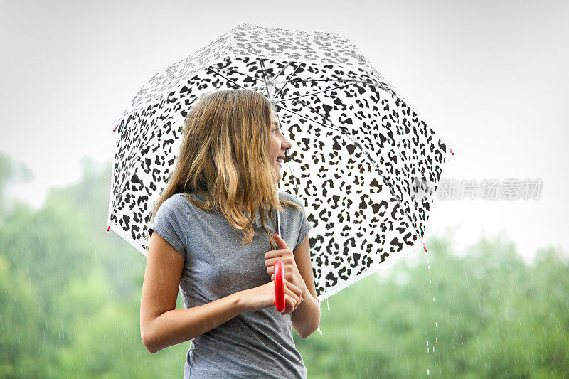 在暴风雨中打着伞的年轻女孩