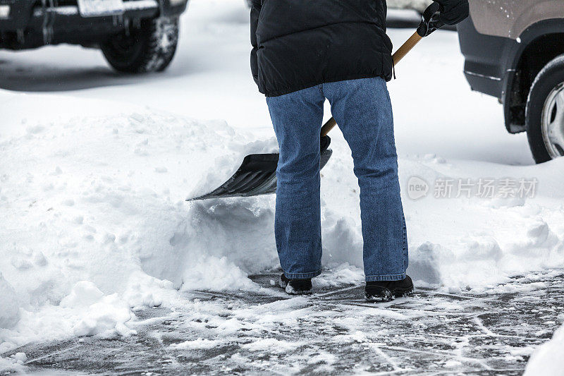 穿着冬季夹克铲人行道雪的人