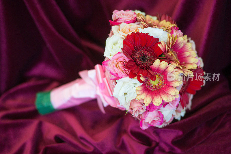 美丽的新娘花束在深红色的纺织品背景