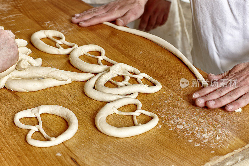 面包店的桌子和两个人的手做椒盐卷饼