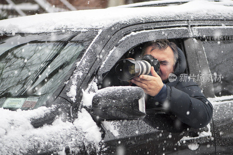 私家侦探在雪地里从车里拍摄监视照片