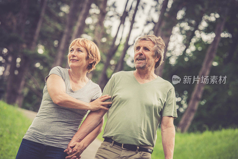 一对老年白人情侣在城市公园里拥抱和散步