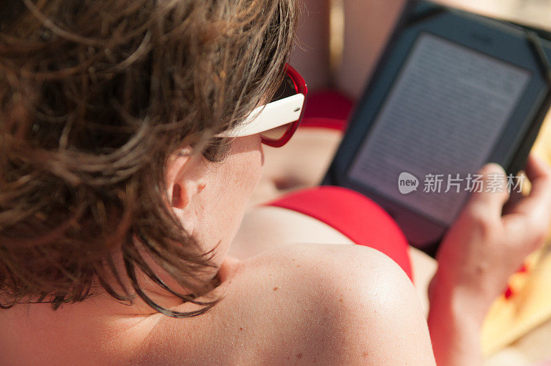 年轻女子在海滩上看电子书