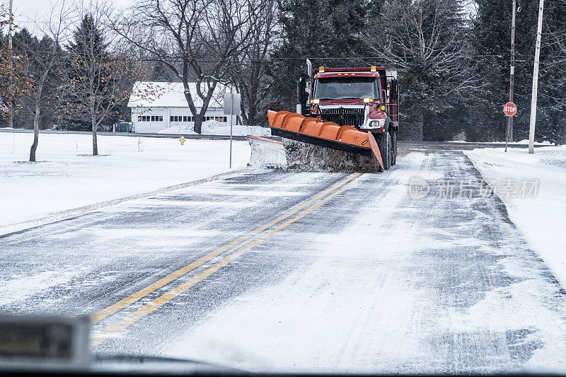 冬季扫雪车驶近寒风吹过的乡村公路