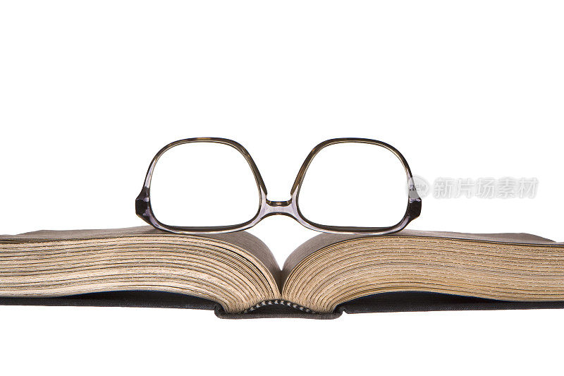 戴着的眼镜搁在一本打开的旧书上