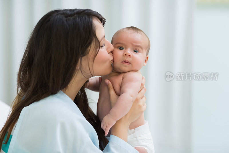 一个女人亲吻一个穿着尿布的婴儿