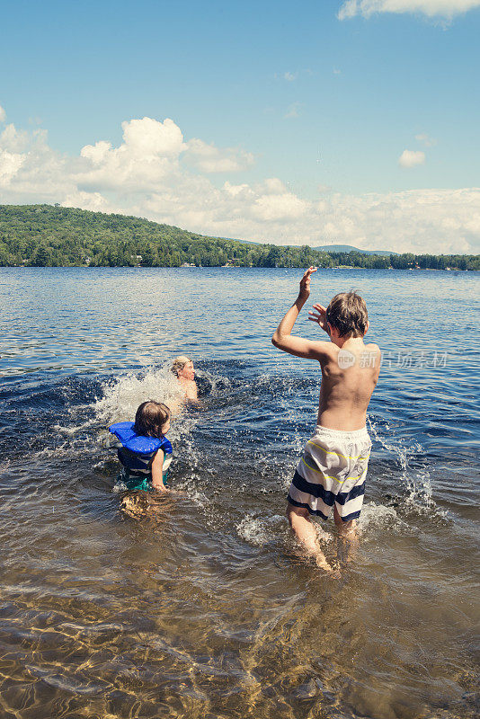 小男孩把妈妈和妹妹泼在湖水里。