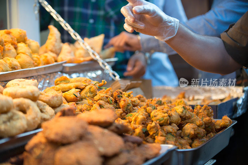 繁忙的街头小吃小贩出售印度炸丸子，萨莫萨和零食