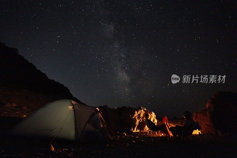 繁星点点的夜空，帐篷，篝火和草地的剪影