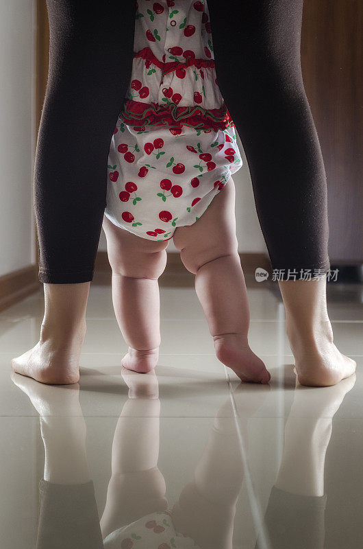 一位母亲教婴儿在室内走路的肖像