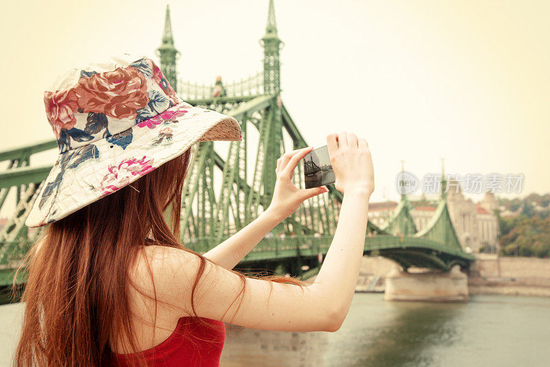 游客在匈牙利布达佩斯自由大桥用智能手机拍照