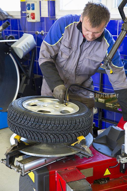 汽车修理工正在换轮胎。准备过冬的车