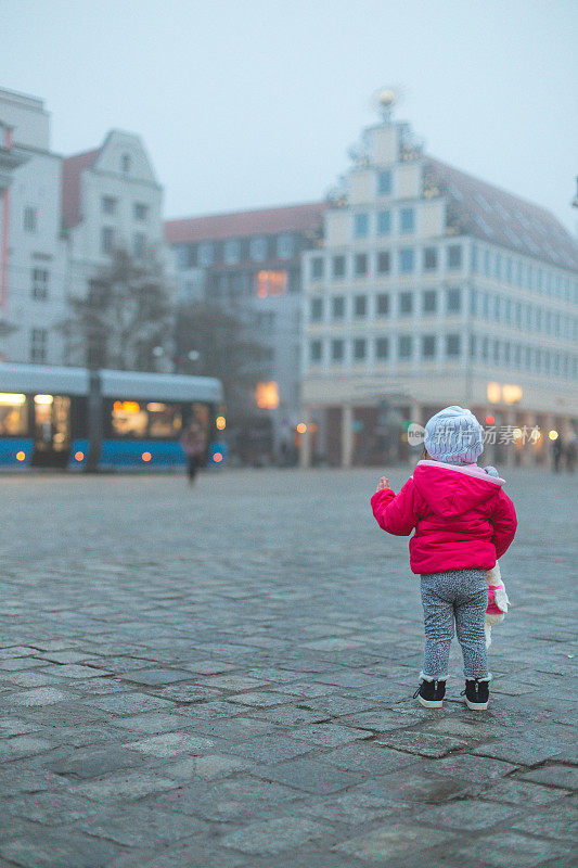 小女孩独自在城市广场向有轨电车挥手