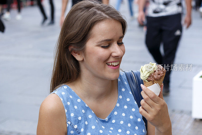 一个好女孩走在城市的街道上，吃着冰淇淋