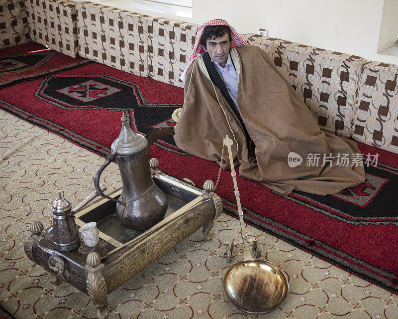 身着传统阿拉伯服饰的成年男子坐在手工地毯上
