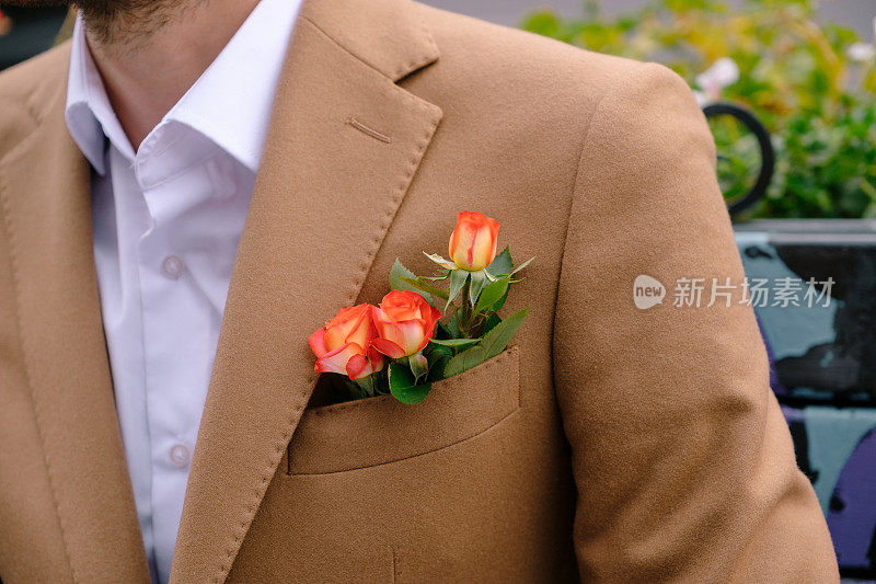 特写男子穿着优雅的夹克，口袋里有三朵玫瑰