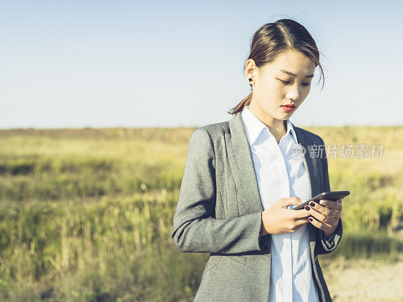 年轻的女商人在乡村公路上使用智能手机