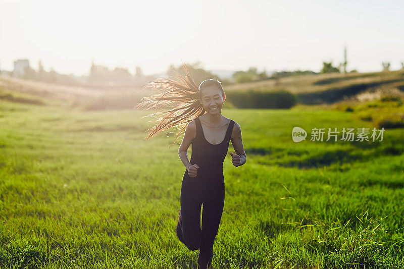 穿着黑色运动服的中国妇女在阳光下跑着相机