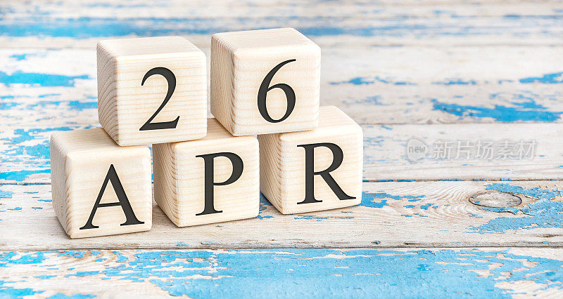 4月26日。木制立方体，日期4月26日在旧的蓝色木制背景。