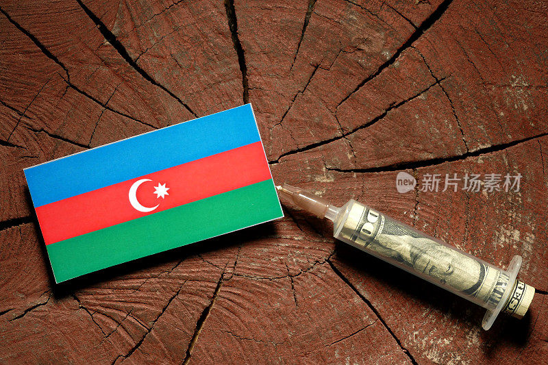 阿塞拜疆国旗在一个树桩上，用注射器在国旗上注射钱