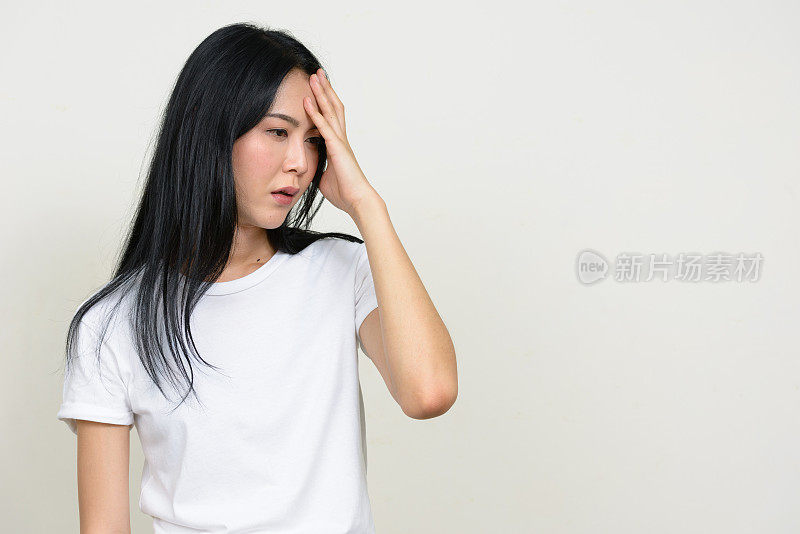 年轻美丽的亚洲女人穿着白色衬衫对抗白色背景