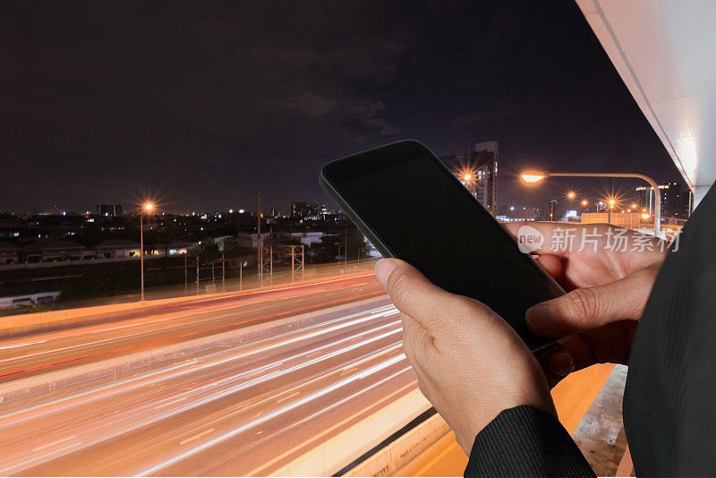 女人手持和触屏智能手机、平板电脑、手机在模糊抽象的夜晚街道背景下作为高速通讯、通讯的技术概念。