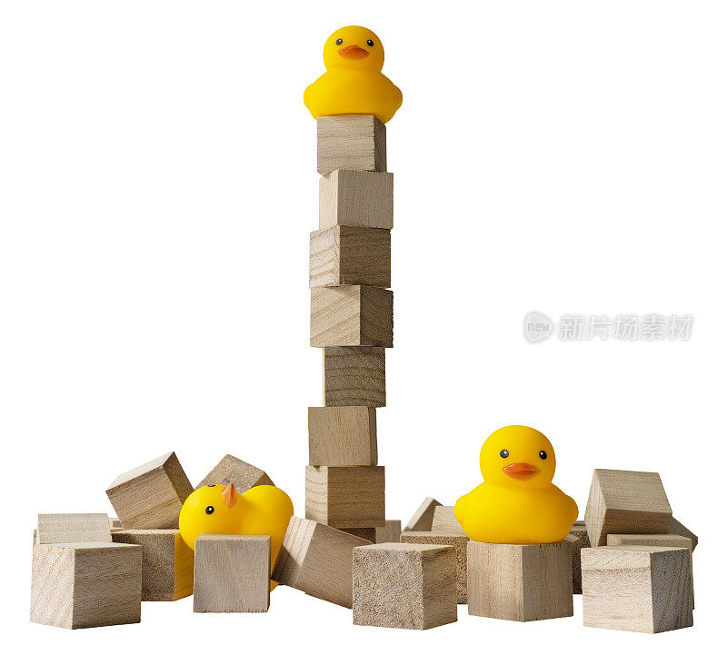 三只橡皮鸭，一只在一个木块塔上，其他的鸭子在一堆倒下的木块上。
